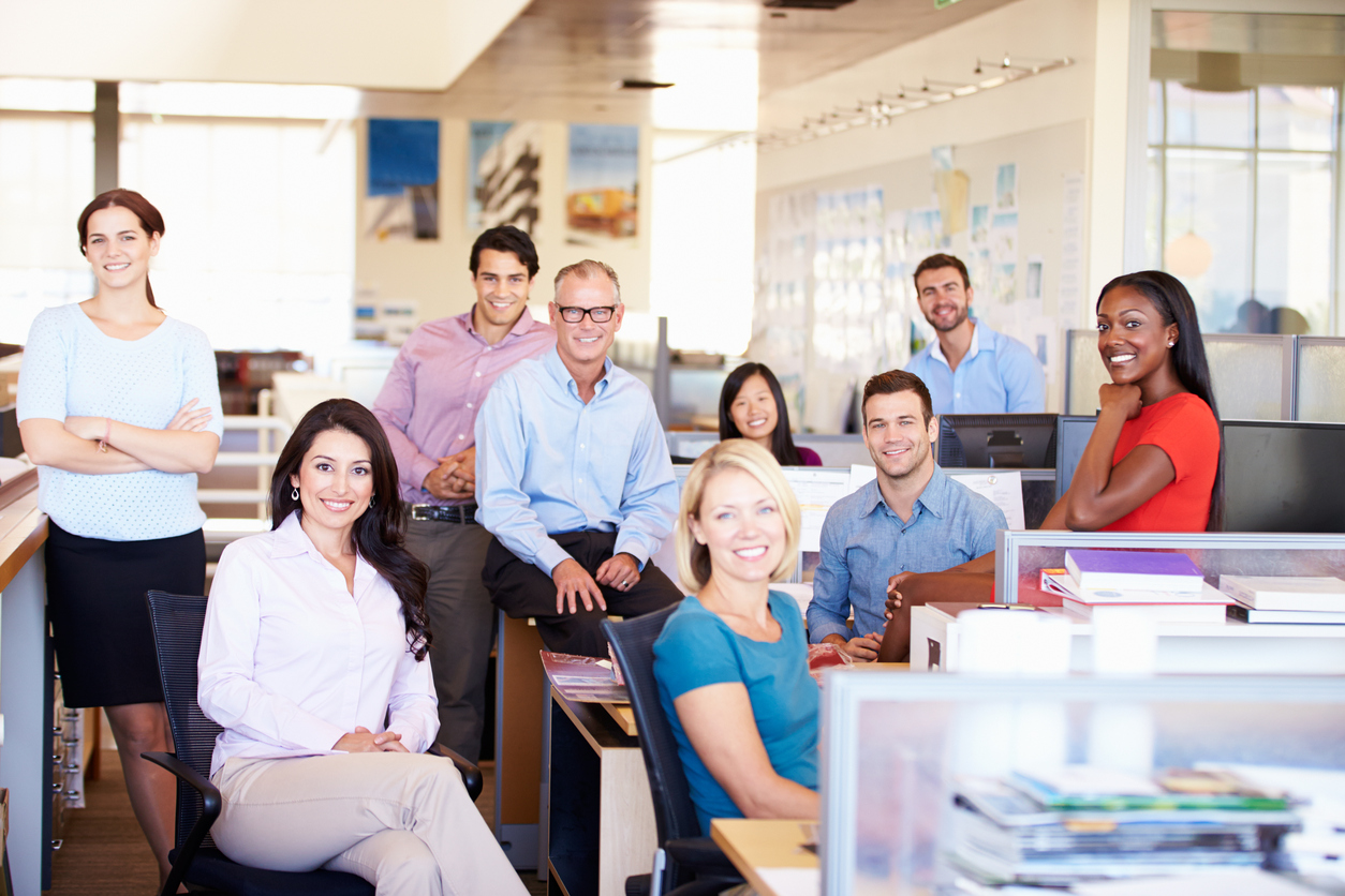 Portrait Of Businesspeople In Modern Open Plan Office Smiling At Camera